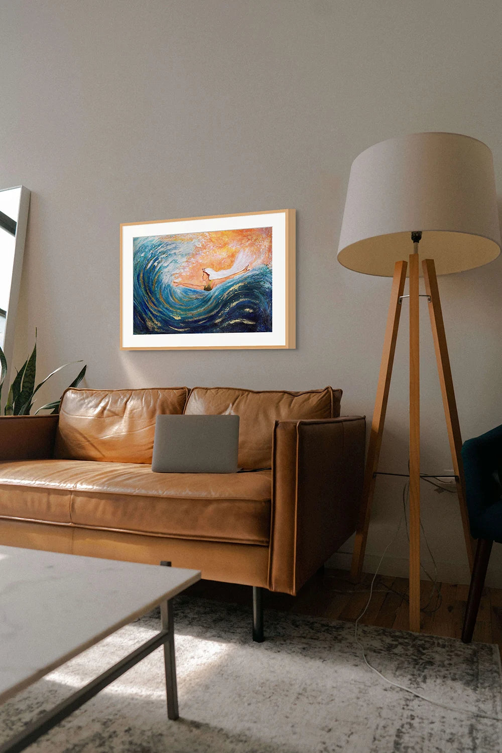 Hue the Artist mixed media large blue and orange print of a woman surfing a big wave, with arms wide, hanging above a caramel leather couch with a large lap
