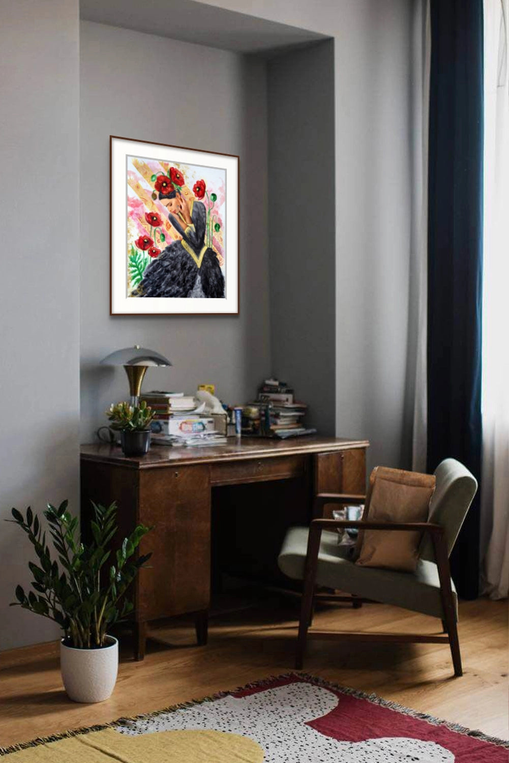 Framed art print by Hue the Artist of a sad woman in black and red poppies hanging in an office nook with a dark wooden desk, green arm chair, rug and pot plant.