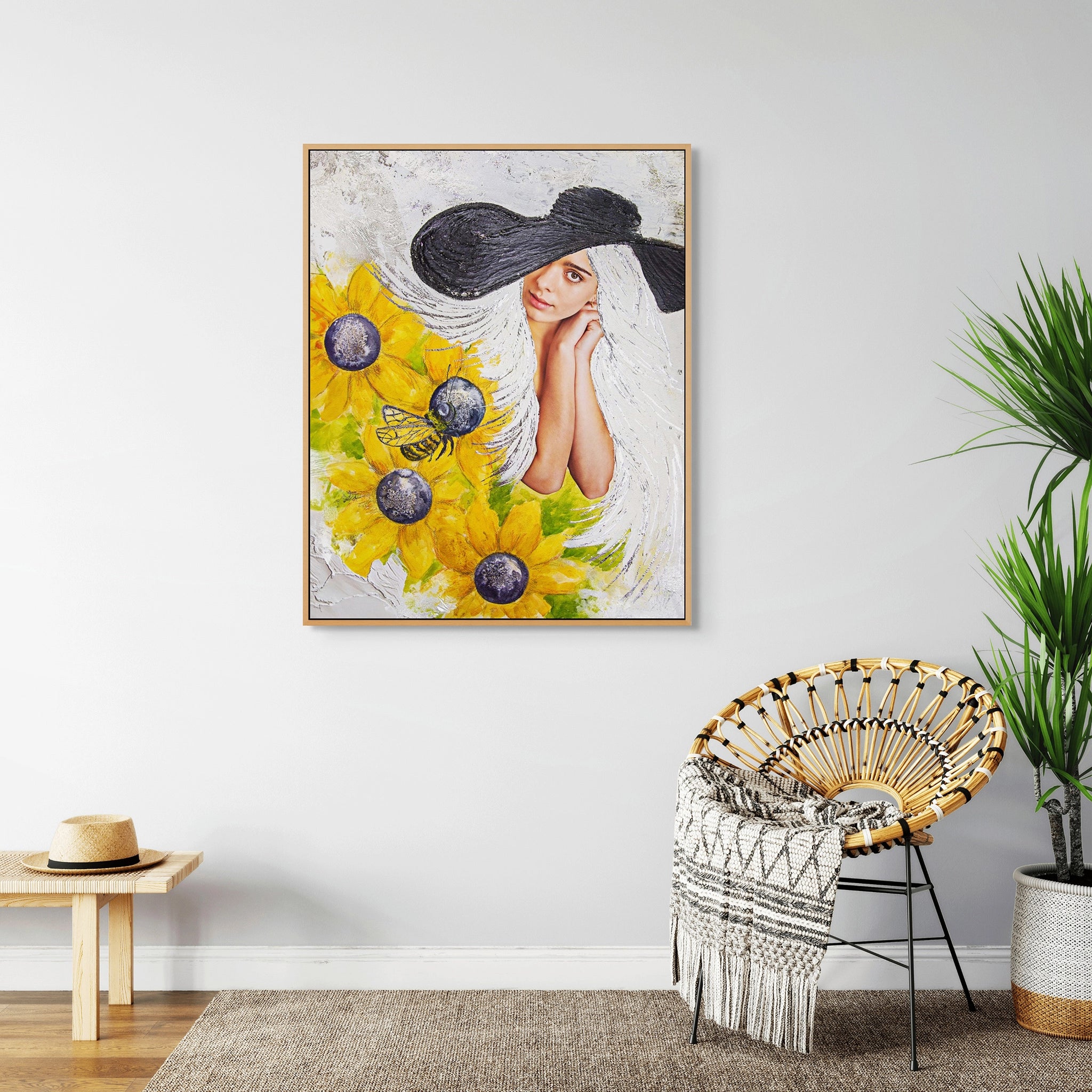 Framed Hue the Artist wall art print of a white-haired woman in a black floppy hat with sunflowers in room with wicker chair, pot plant, and bench with a straw hat.