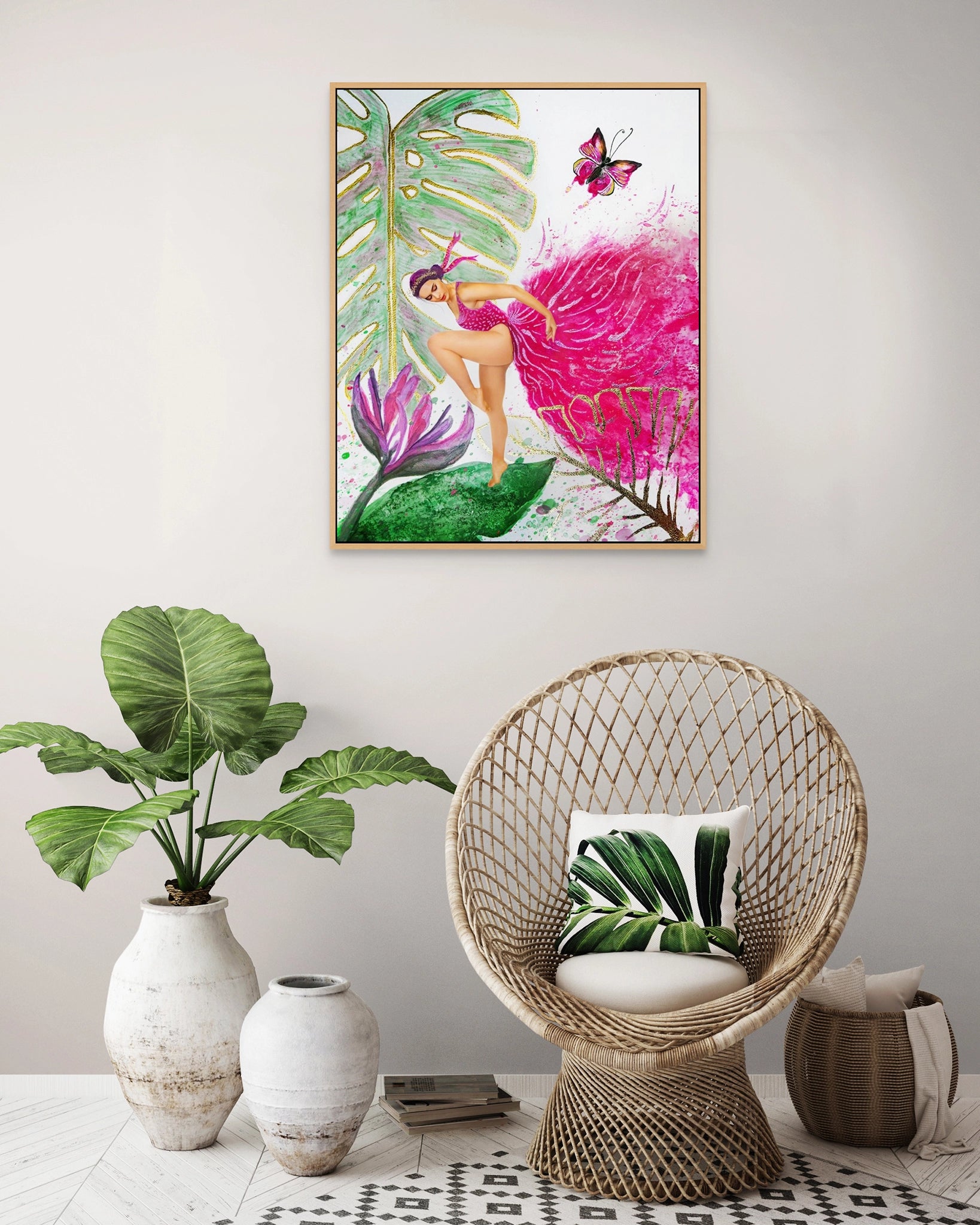 Framed Hue the Artist Canvas of woman in bright pink gown hangs above a wicker chair and house plans in white pots.